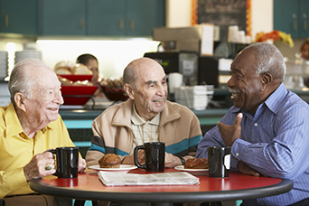Photo of three elderly men in a coffee shop.