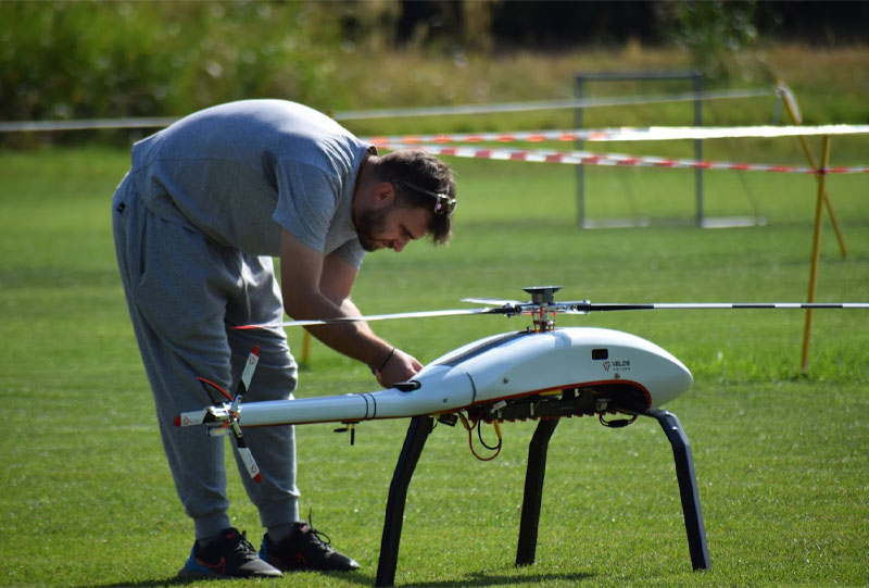 A person crouched by a drone