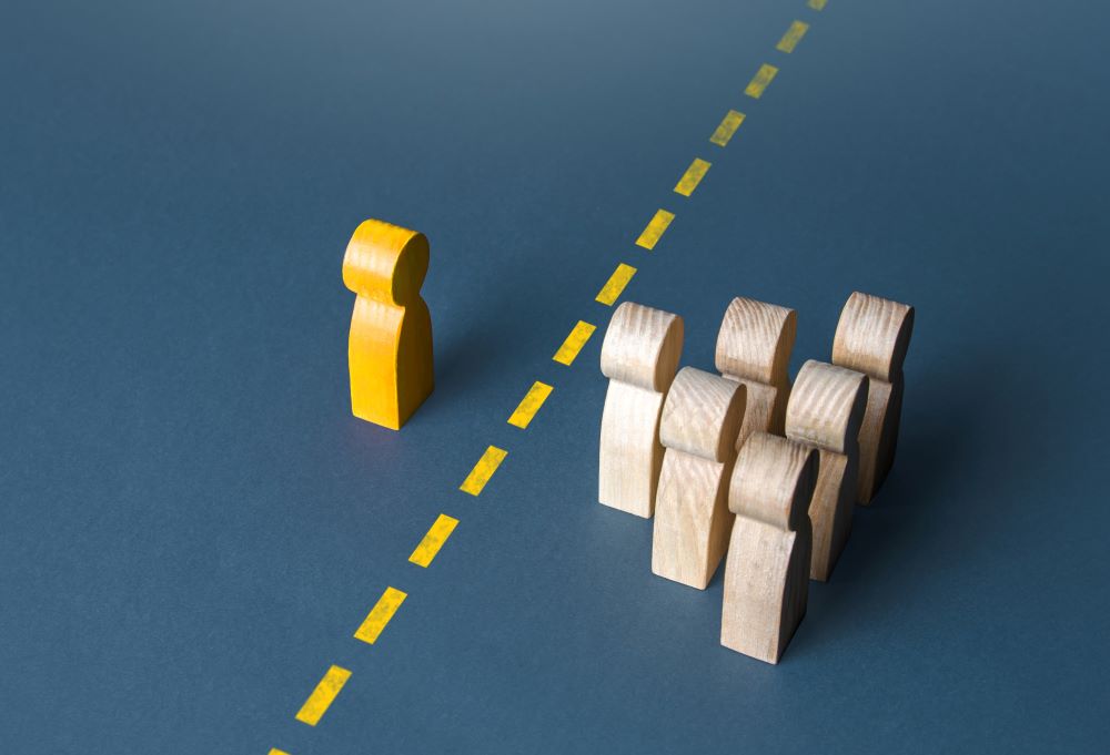 a yellow wooden person and beige wooden people are separated by a yellow line