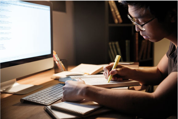 A photograph of a student working at a desk at night.