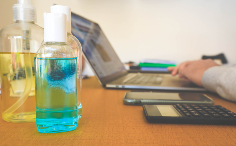 Blue bottles of hand sanitiser on a table during work from home to protect against covid-19