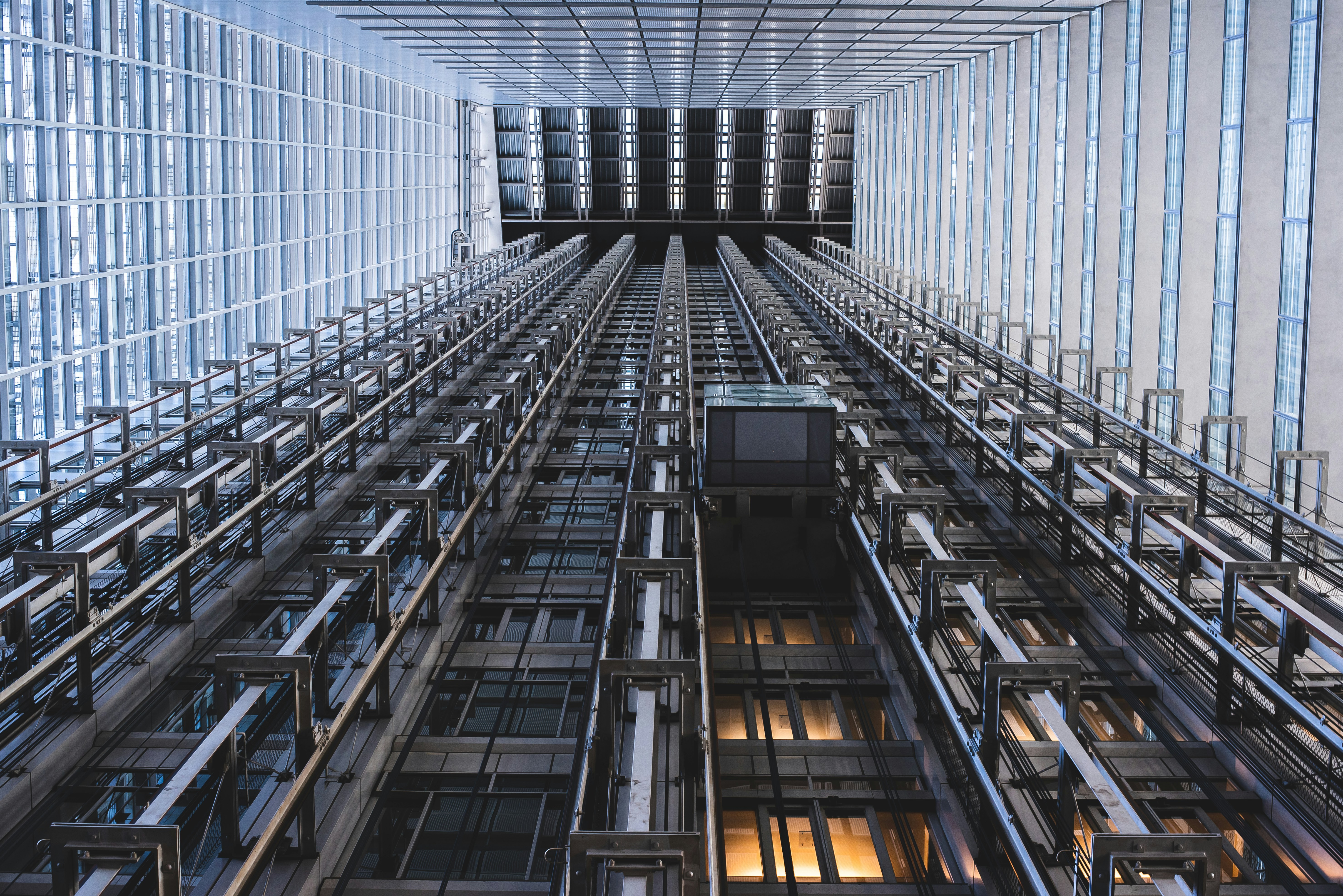 Worm's eye view of several exposed lifts in a commercial building in Tokoyo with lots of glass.