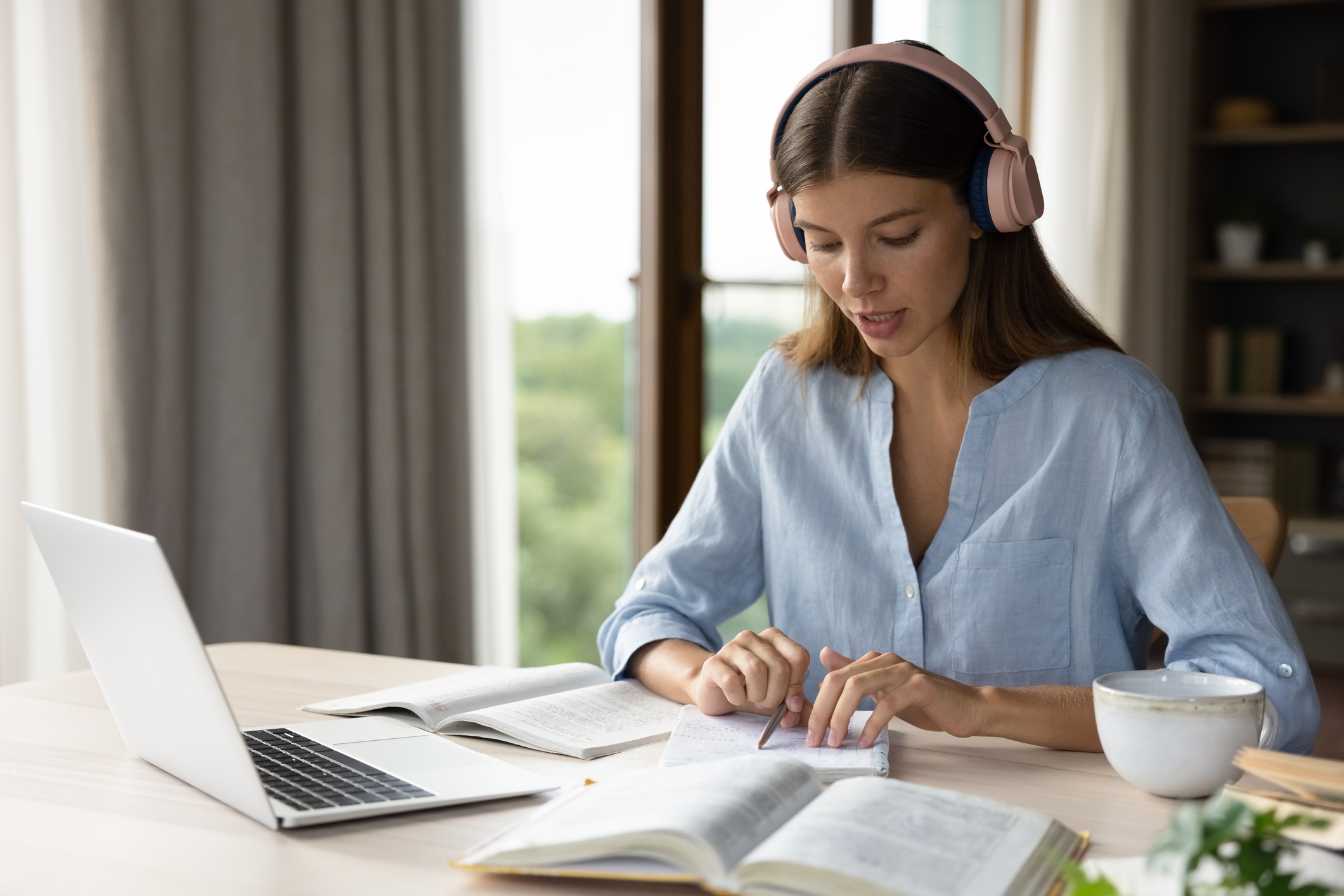 Focused student reading aloud at her desk with headphones on