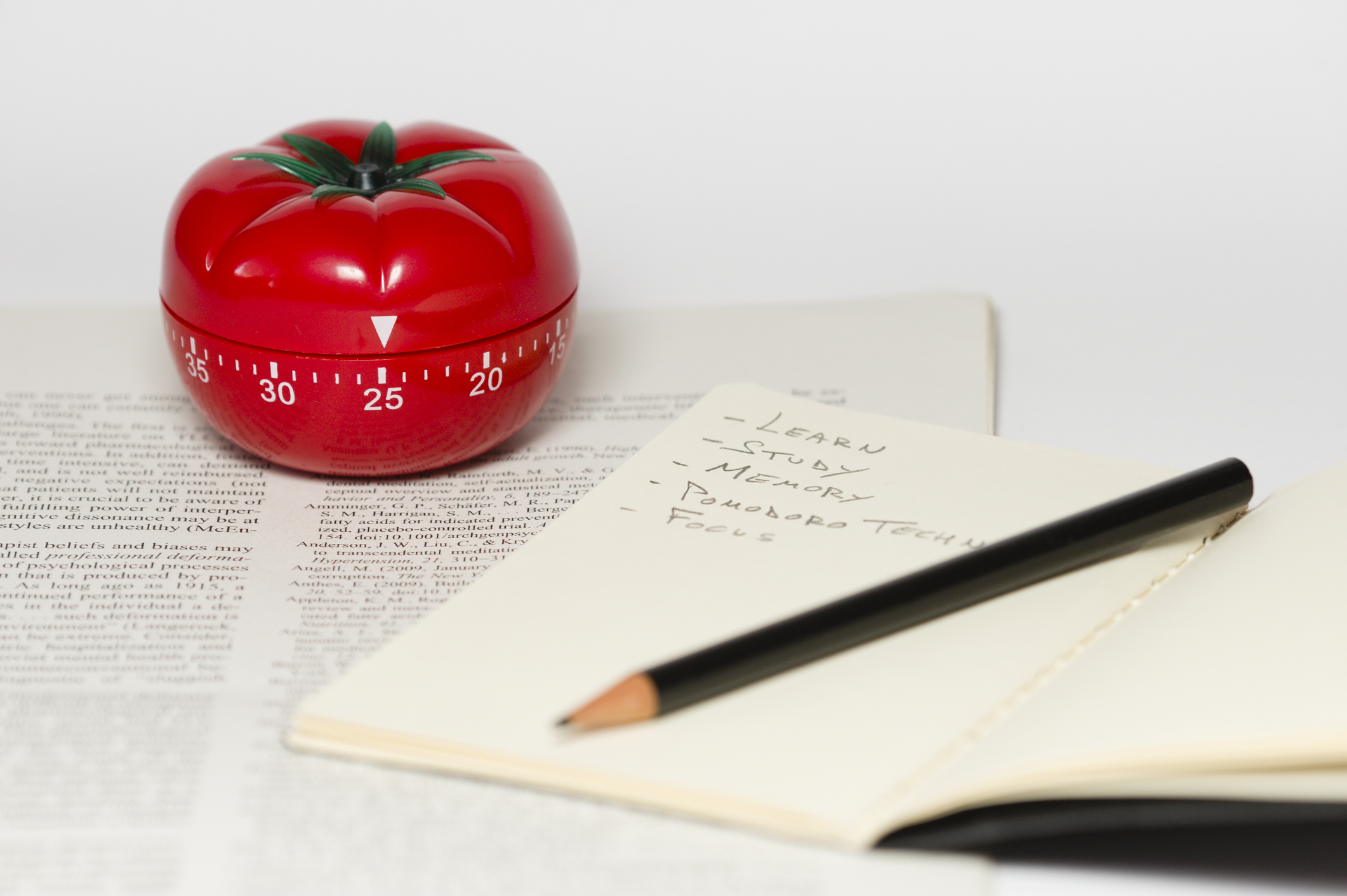 Tomato kitchen timer with notes and a pencil to convey the Pomodoro (tomato) technique