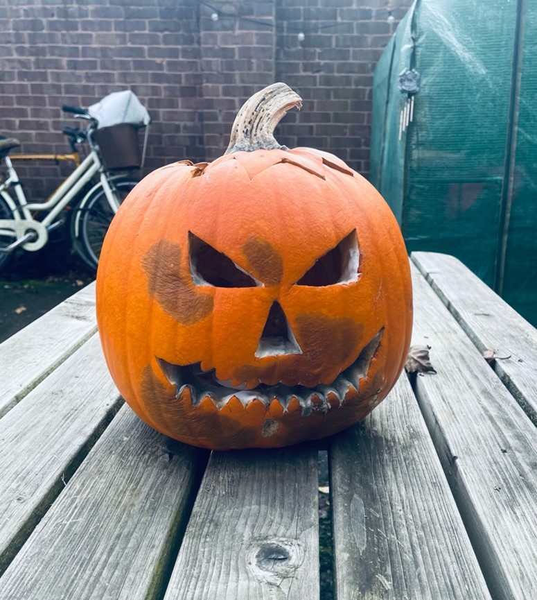 A carved pumpkin on a table outside