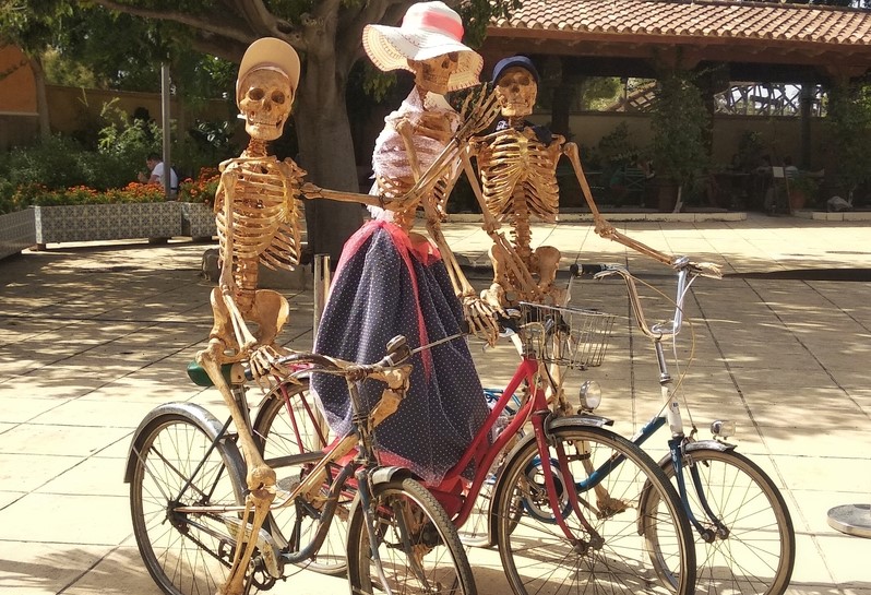 Three Halloween skeletons on a bike in party in a city park