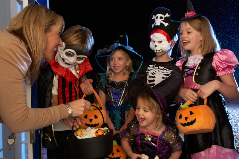 Children dressed up for a Halloween party - trick or treating at a door