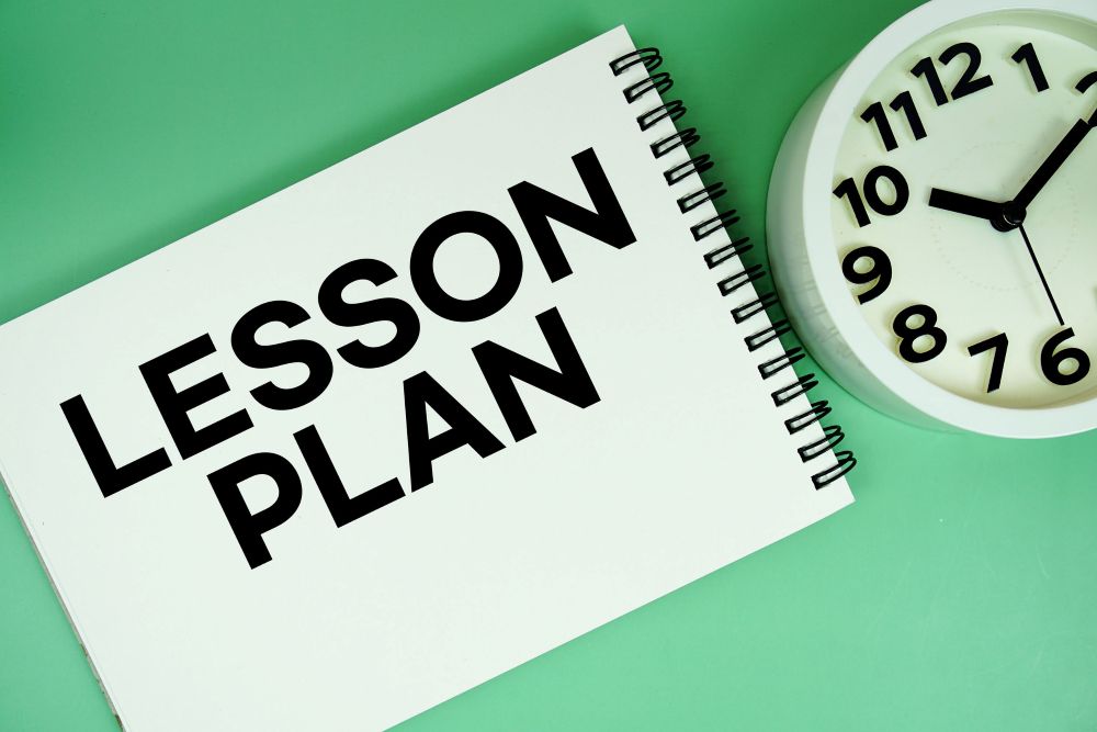 Lesson Plan text with alarm clock flat lay on green background