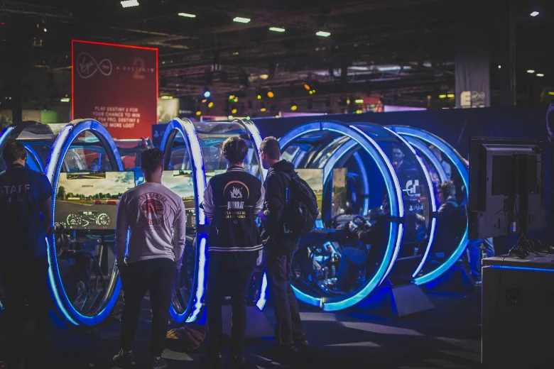 Esports gamers stand watching computer screens at an esports tournament.