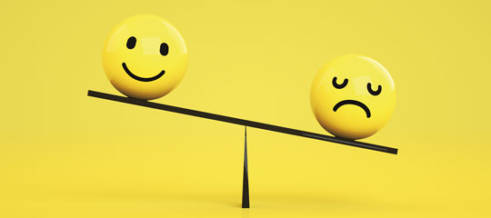 A colour image of a balancing scale supporting two faces; one happy and one sad.