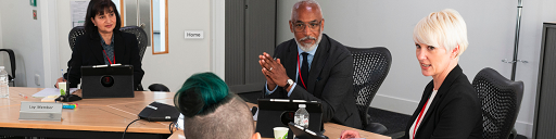 Tri aelod o banel/pwyllgor yn gwrando ar dyst.