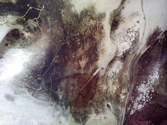 Prehistoric cave painting, including human hands.