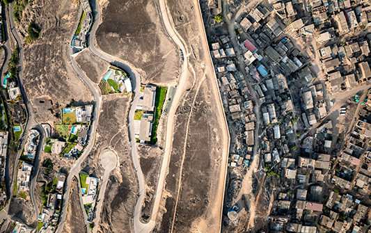 A birds eye view photograph of the ‘The Wall of Shame’ in Lima, a kilometers-long barrier of concrete and barbed wire.
