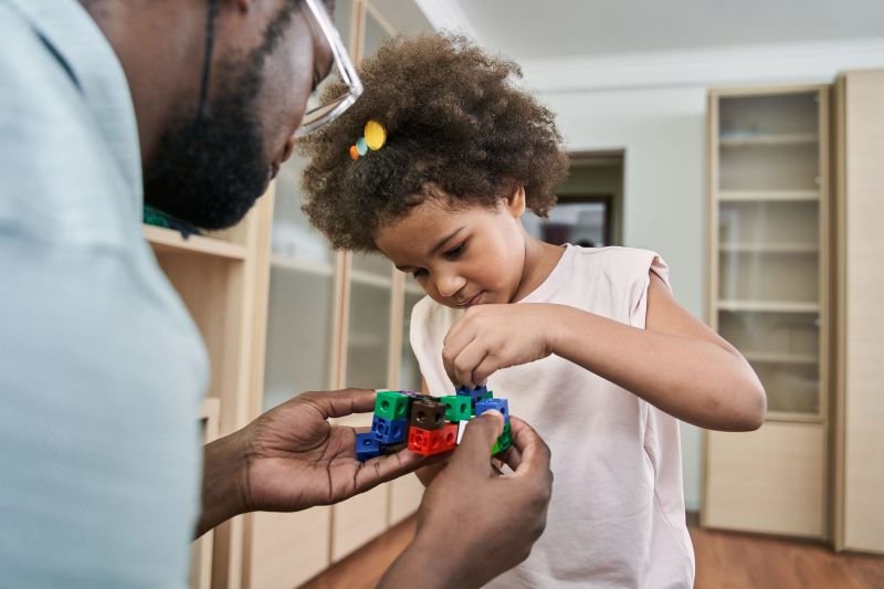 Young autistic black girl building blocks with her dad
