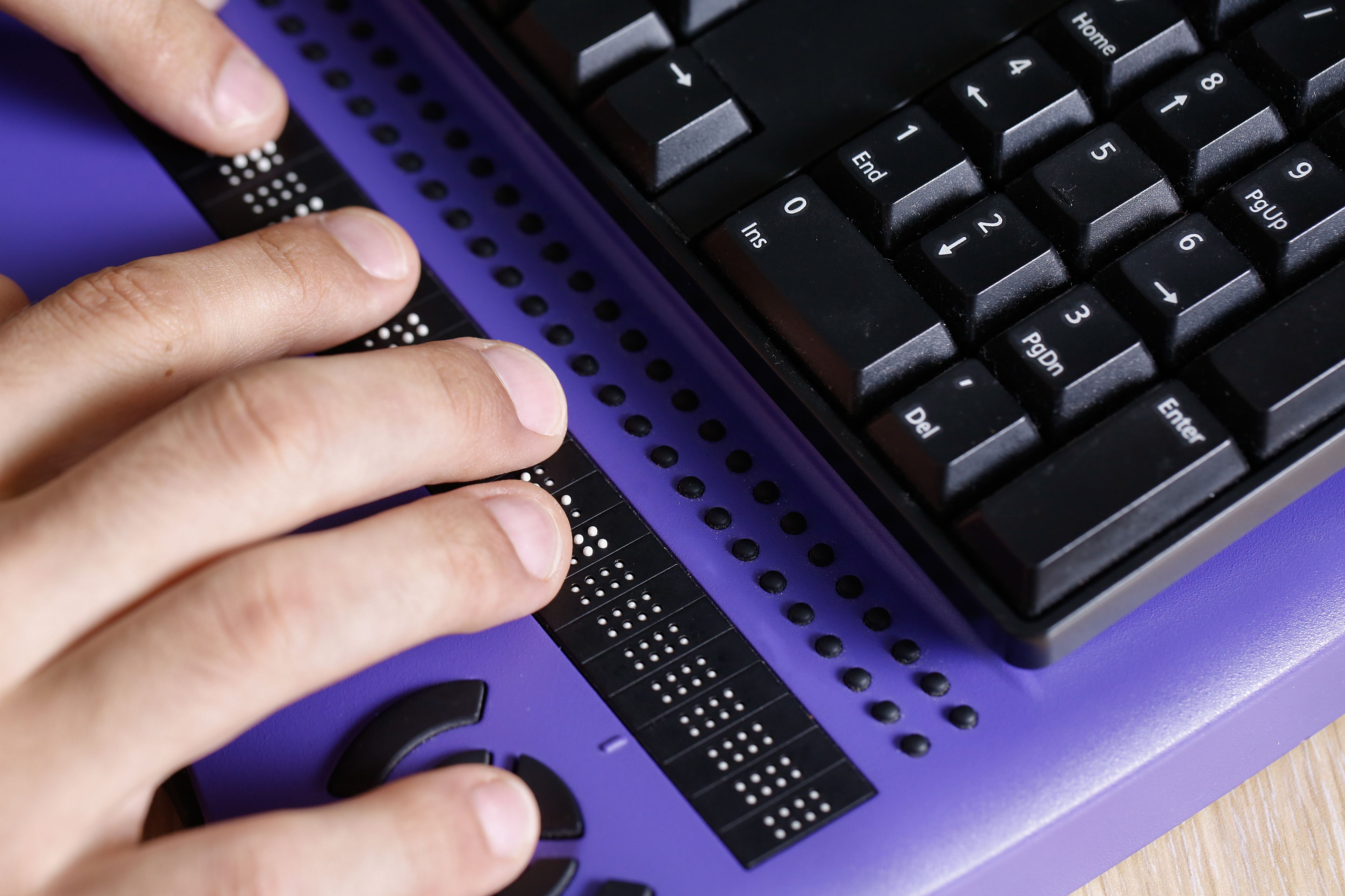 Hands of a person using a computer with braille computer display