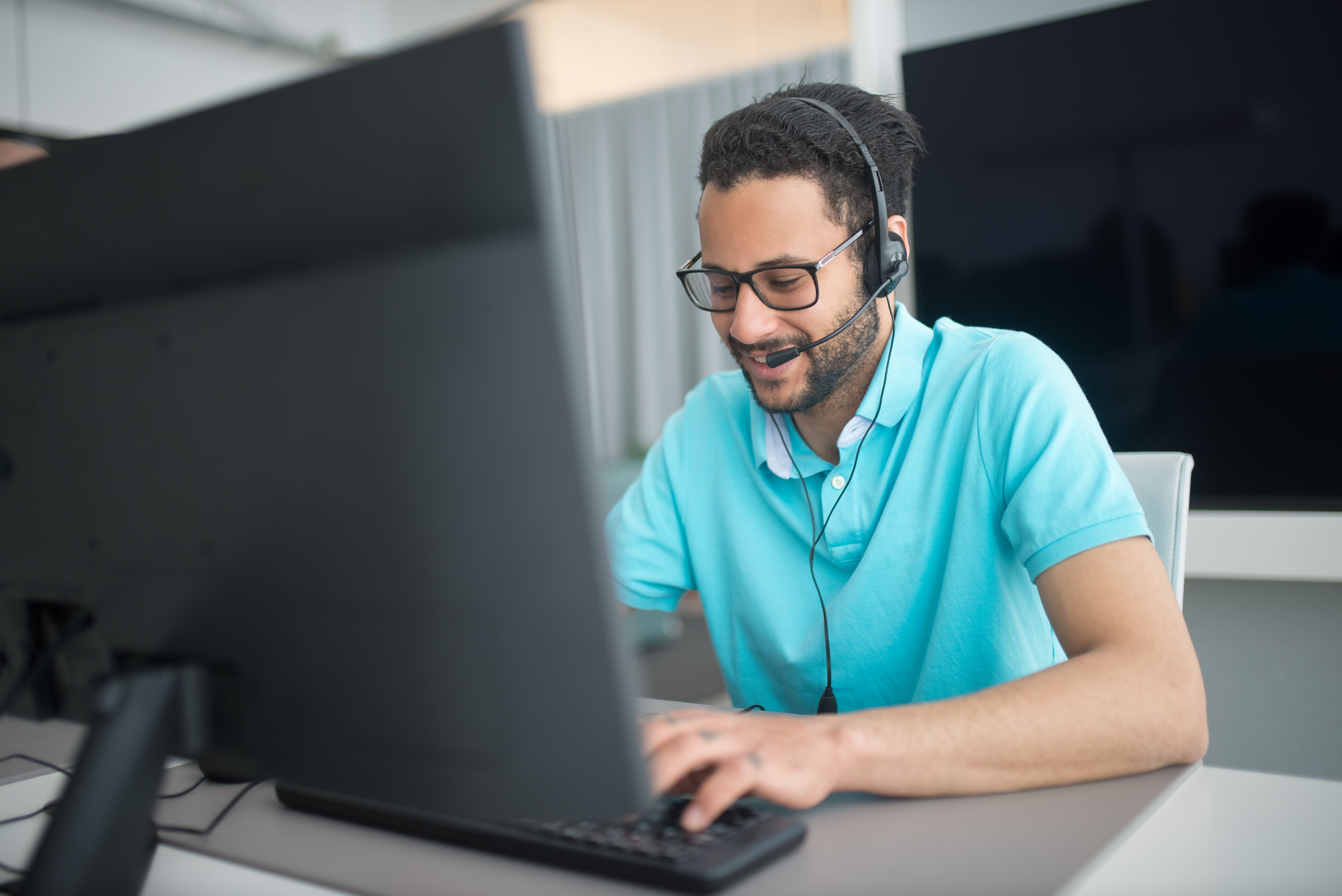 Man sitting at a table in front of a computer with a head set on 