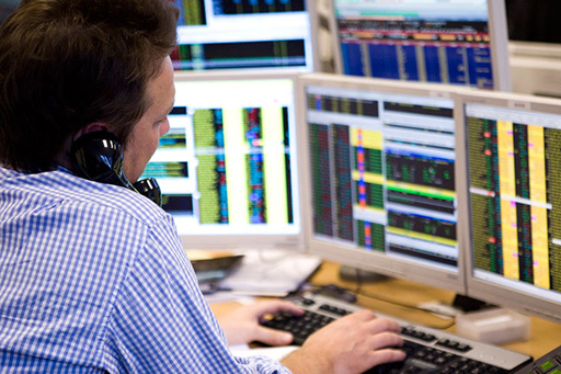 The image is of a trader at his desk viewing trading screens.