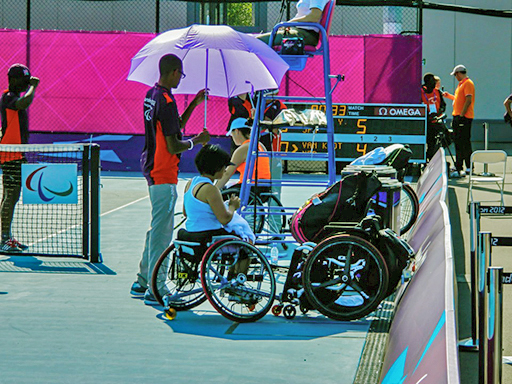 A volunteer creating shade by holding an umbrella over a contestant at the London 2012 Paralympics.