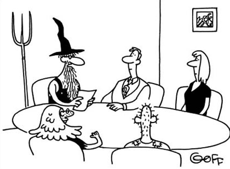 This is a cartoon image of a meeting room. Five people are sitting around an oval table. At the far end, facing forward, are a man and a woman sitting next to each other, both dressed smartly. Sitting opposite, facing them, are another man and woman, sitting next to each other, who are shown as being scruffier looking. At the head of the table, on the right hand side, is a figure with a long beard and glasses, dressed in a wizard’s hat and vest top. Behind him, there is a trident propped standing against the wall. He is reading from a piece of paper, which he is holding up in front of him. The caption reads ‘After the merger, you may notice a few changes in our corporate culture.’