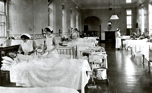 Figure 5 Nurses on a ward, Leith Hospital, Edinburgh, 1917. This image encapsulates the order and cleanliness of the hospital ward, with its rows of beds and polished floor. This picture is unusual in that it does not show the medical staff, only the nurses, some of whom are tending to a patient. The trolley of dressings and bottles is visual evidence of how the role of nurses had expanded from providing care to undertaking medical treatment.