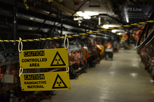 This is a photograph with a factory setting in the background and a sign saying ‘CAUTION CONTROLLED AREA. CAUTION: RADIOACTIVE MATERIAL’ in the foreground.