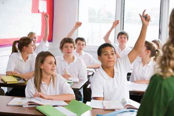 Children in a classroom, some with their hands in the air