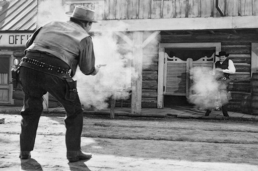 A photograph from a film scene in which two people in the Wild West are shooting at each other.