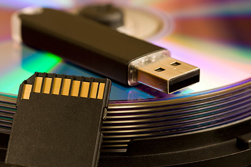 An image of a USB memory stick and a memory card on top of a pile of discs.