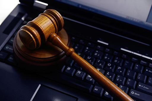 A judge's gavel on top of a computer.