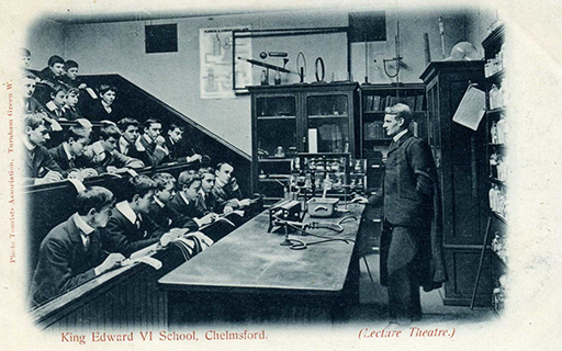 An image of an old black and white photograph of students and a teacher inside a lecture theatre.