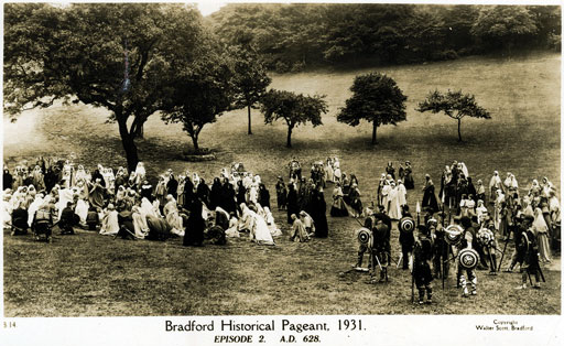 Photograph of a historical pageant, captioned ‘Bradford Historical Pageant. 1931.’ Crowds of people are shown gathered on a field near some trees. A group of people are dressed like they are about to give a performance of a historical battle.