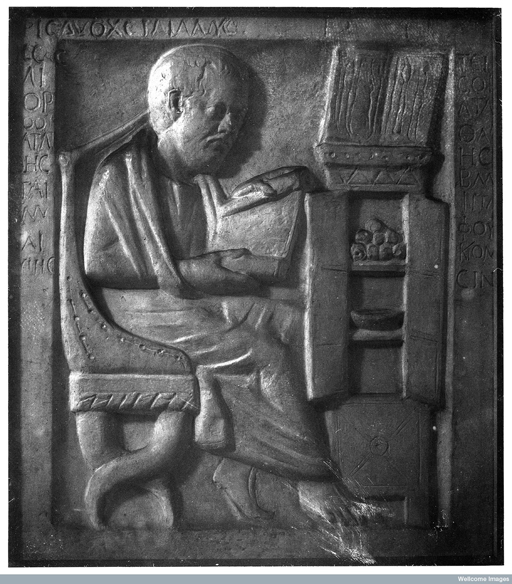 Wood-carving of a doctor reading a scroll.