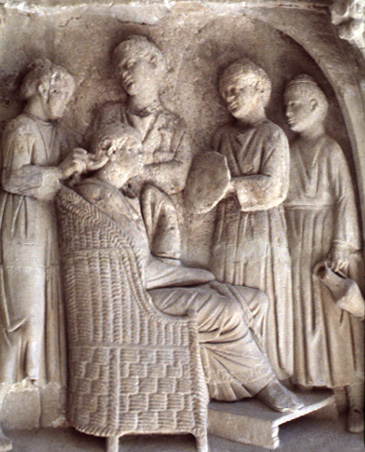 Carved stone relief of a woman seated in a chair, being attended to by four maidservants.
