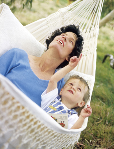 A photograph of a small boy and his mother lying in an outdoor hammock.