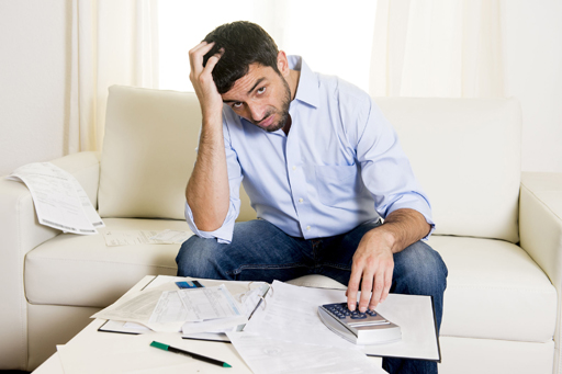 This photograph shows a confused looking man surrounded by financial statements.