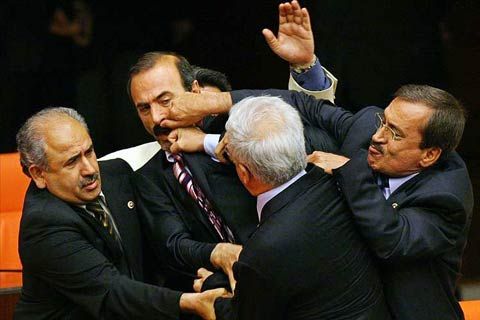 An image of a group of men all dressed in suits fighting with each other.