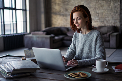 Image of a woman working at home on a laptop on a table.