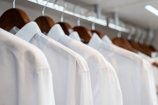 A row of white business shirts hanging on a rail.