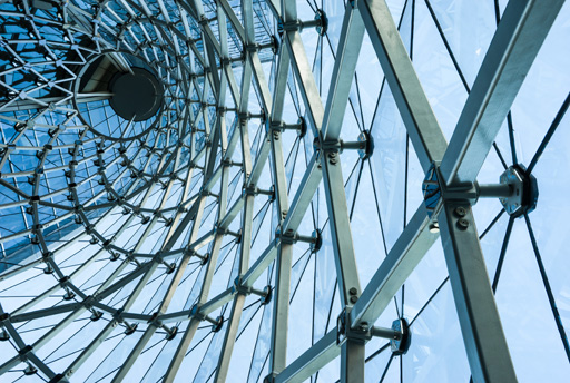 A complex, spiralling metal framework supporting a glass roof on a building.
