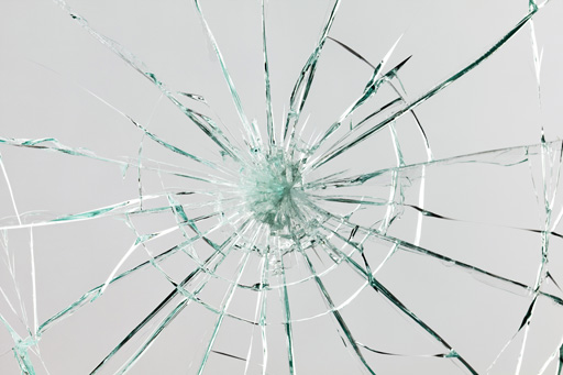 A pane of glass with cracks radiating out following the impact of something at its centre.