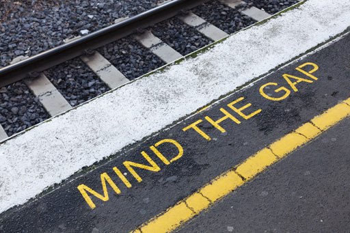 Mind the gap is written in yellow paint on the ground next to a railway track