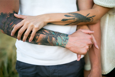 A man and a woman with tattooed arms.