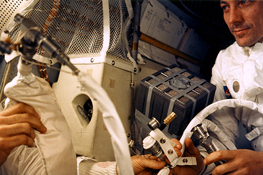 View of Apollo 13 astronauts changing one of the modified LiOH cannisters.