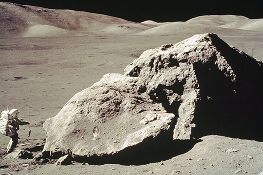 Image of Harrison Schmidt sampling a large boulder during the Apollo 17 mission.