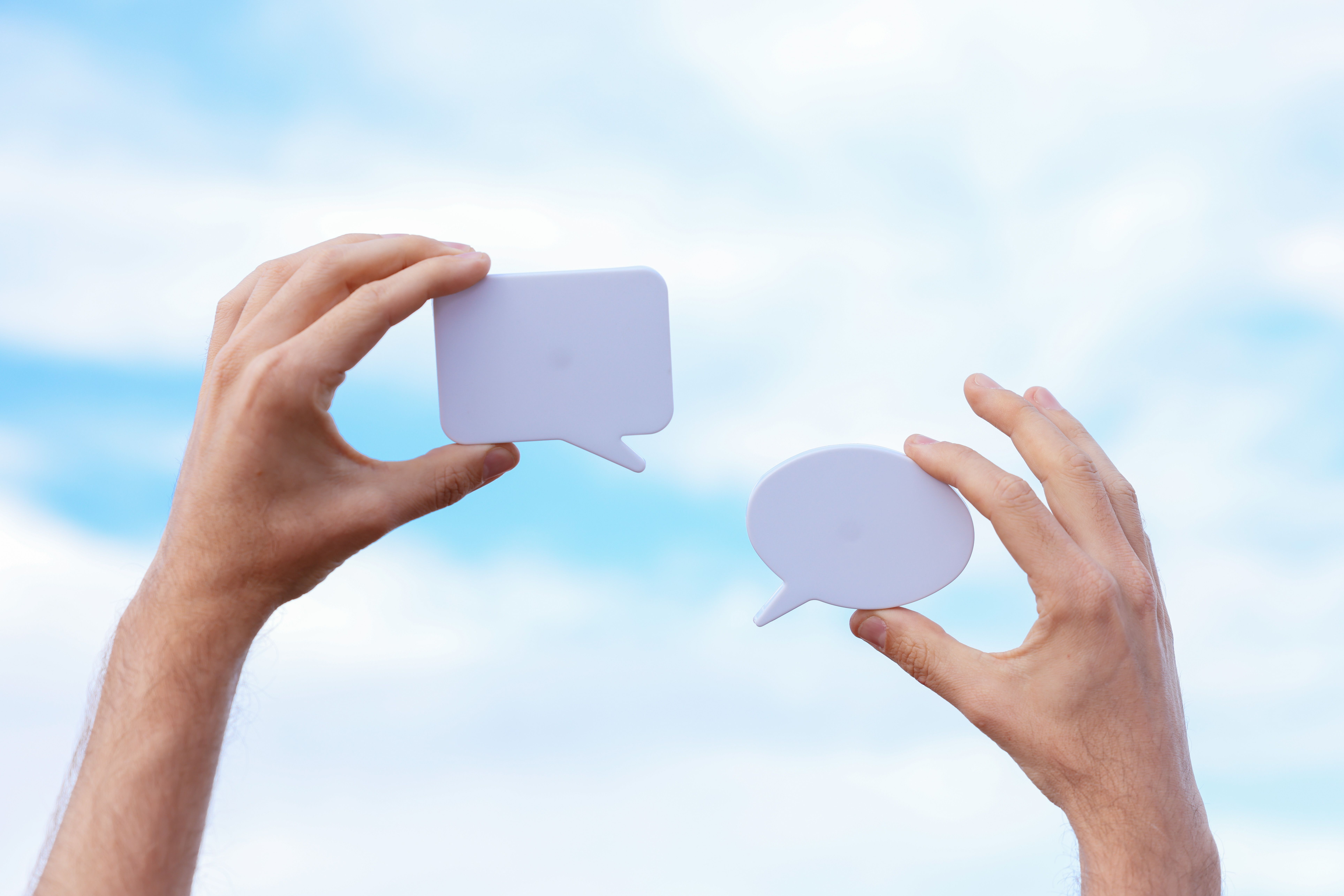 hands holding up two empty speech bubbles