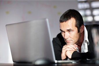 Man looking thoughtfully into laptop screen
