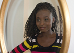 Photograph of reflection in a mirror of a smiling young black woman