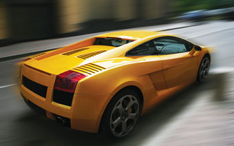 Photo of yellow sports car driving fast on a road