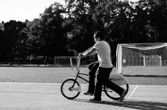 Black and white photo of a man helping a child ride a bike