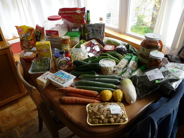A table in a home that is covered with over 30 ingredients (vegetables, spices, rice) to prepare a Korean dinner.